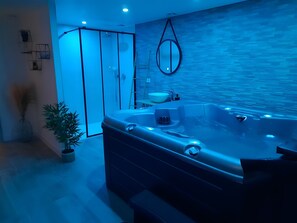 A modern bathroom with a large bathtub, a shower area, and a sink.