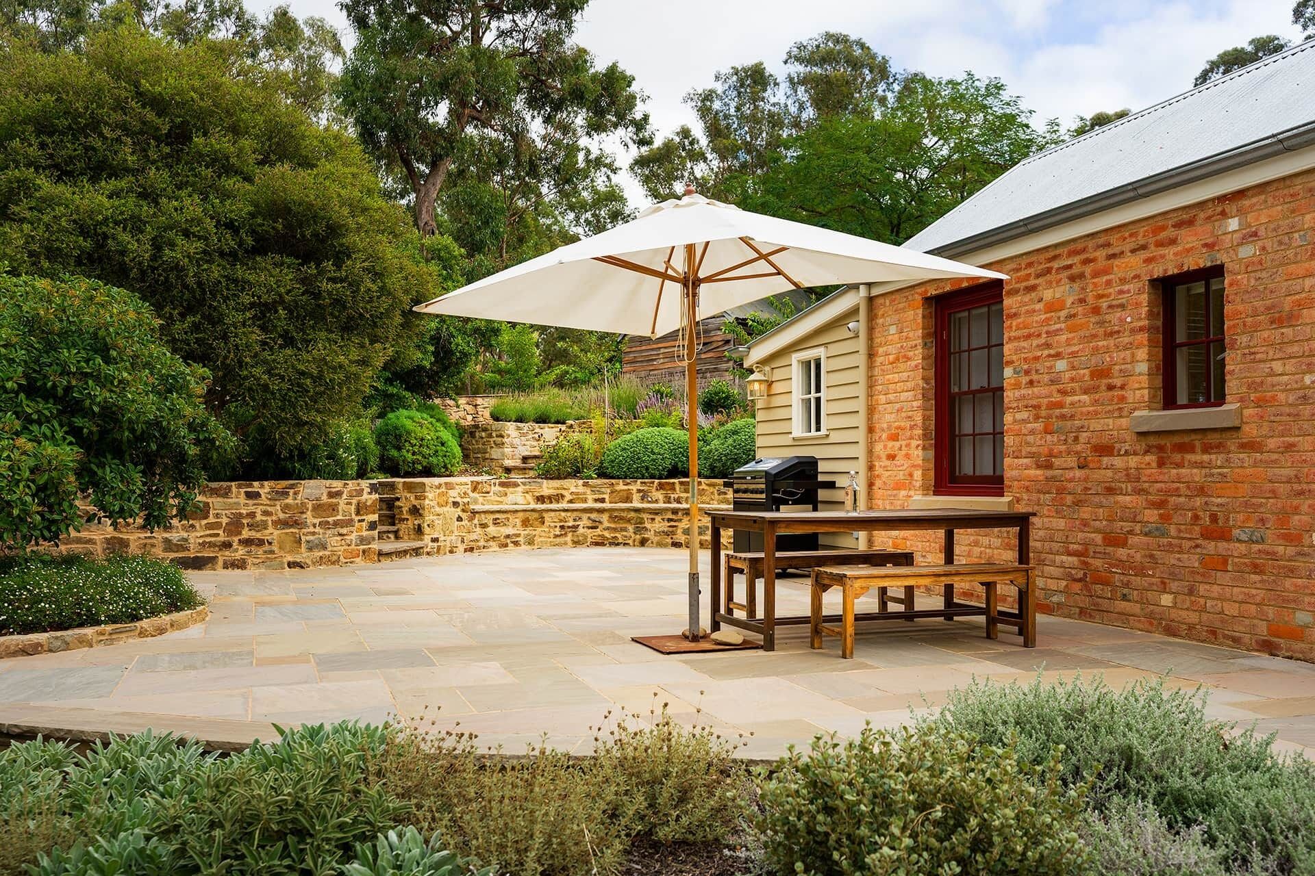 A patio with a table and chairs, a barbecue grill, and a large umbrella.