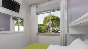 A bedroom with a bed, a window with curtains, a mirror, and a television on the wall. - Ca di Valle Retreats (Cavallino-Treporti)