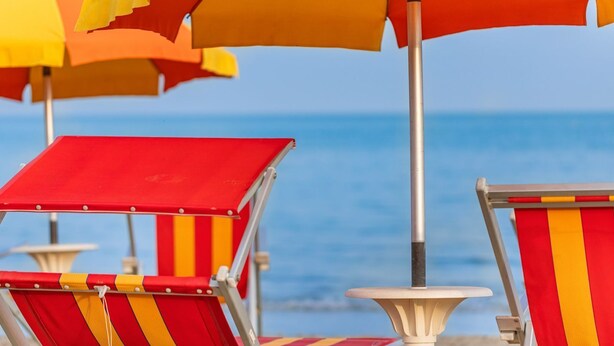 Beach chairs with striped red and yellow fabric, metal poles, and umbrellas in orange and yellow. - Ca di Valle Retreats (Cavallino-Treporti)