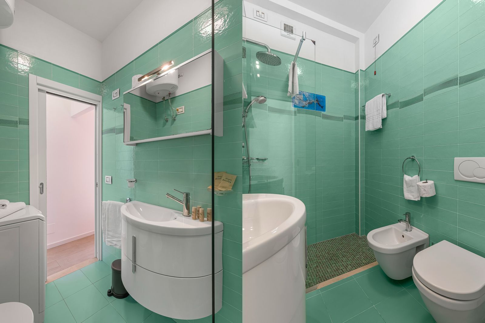 A bathroom with a shower, sink, bidet, and toilet.