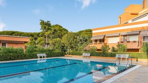 A swimming pool with clear blue water, surrounded by a tiled deck and benches. - Ca di Valle Retreats (Cavallino-Treporti)