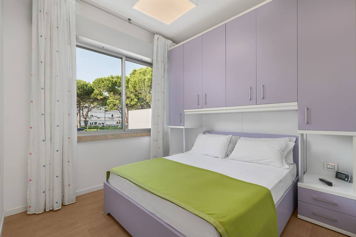 A bedroom with a bed, a window, and purple cabinets.
