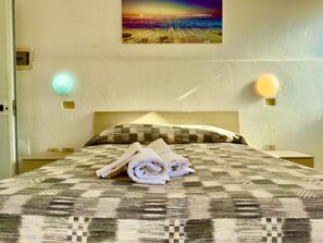 Ein Hotelzimmer mit Bett, einem Bild an der Wand und zwei Wandleuchten.