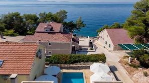 Uma área residencial costeira com casas de telhado em terracota, uma piscina e vista para o mar.