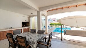 Un espace patio comprenant une table à manger, des chaises, une piscine et un coin salon abrité.