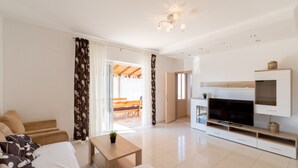 Una sala de estar moderna con un sofá, una televisión y una zona de comedor con una mesa y sillas.