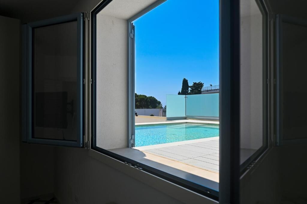 A room with a window overlooking a swimming pool.