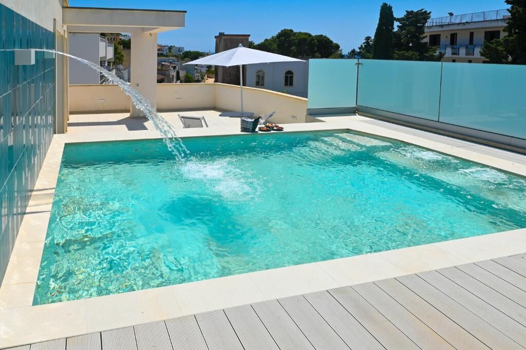 A rectangular swimming pool with clear water, surrounded by a wooden deck.
