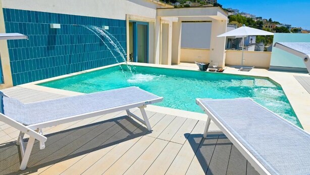 Piscina com duas espreguiçadeiras e um elemento aquático.