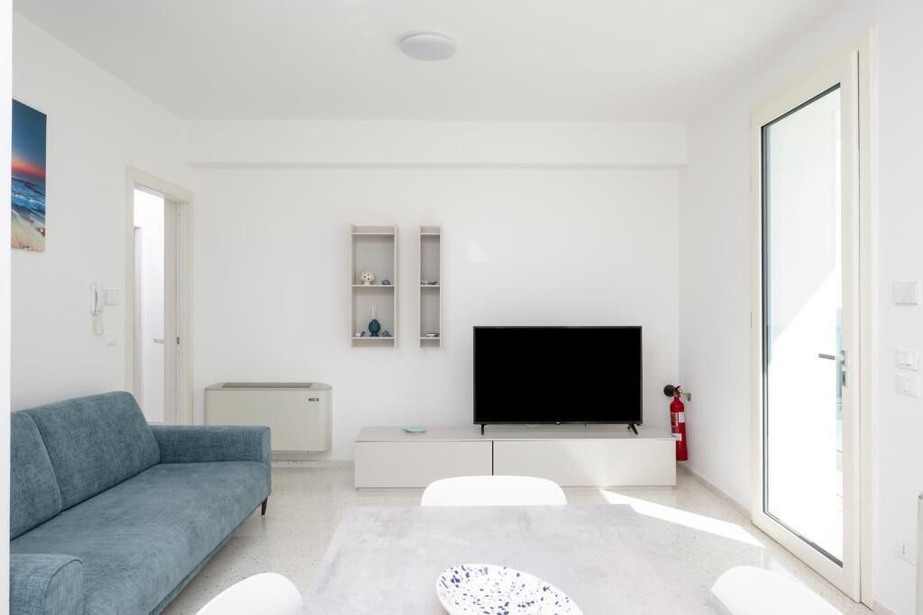 A modern living room with a sofa, a flat-screen TV, a coffee table, and a sliding glass door.