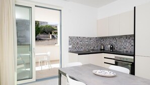 Uma cozinha moderna com uma porta de vidro que dá para uma área externa com mesas e cadeiras.