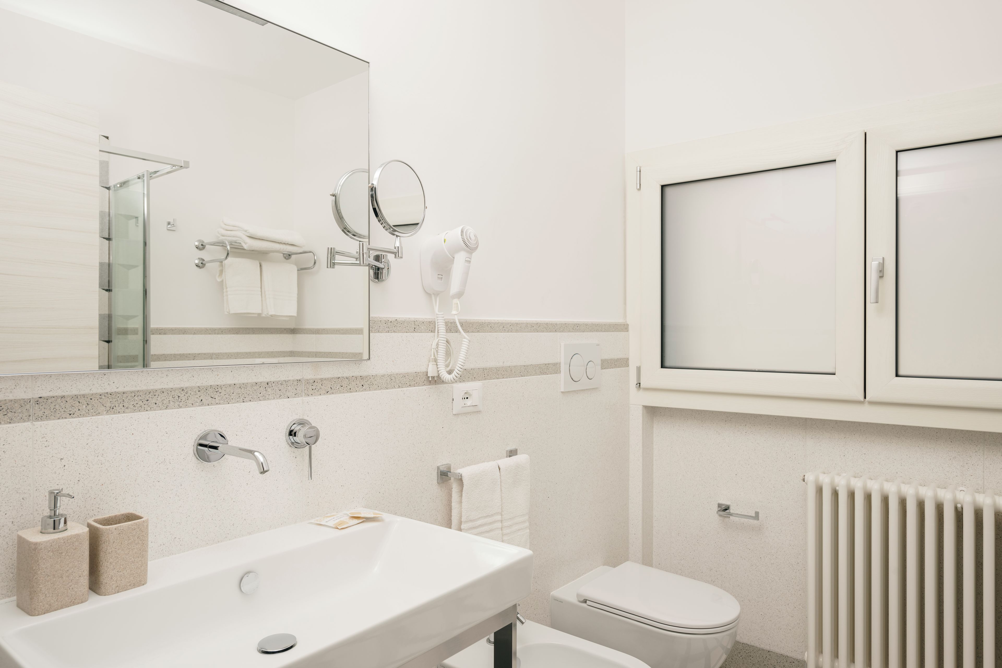 A modern bathroom with a sink, mirror, towel rack, and toilet.