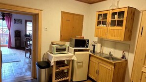 A small kitchen with wooden cabinets, a microwave, a toaster, and a refrigerator. - Pension Leopoldine (Hallstatt)