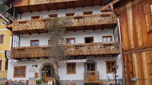 A multi-story wooden building with balconies, a sign for 'Vension Georgopoldine,' outdoor seating, and a mountain backdrop. - Pension Leopoldine (Hallstatt)