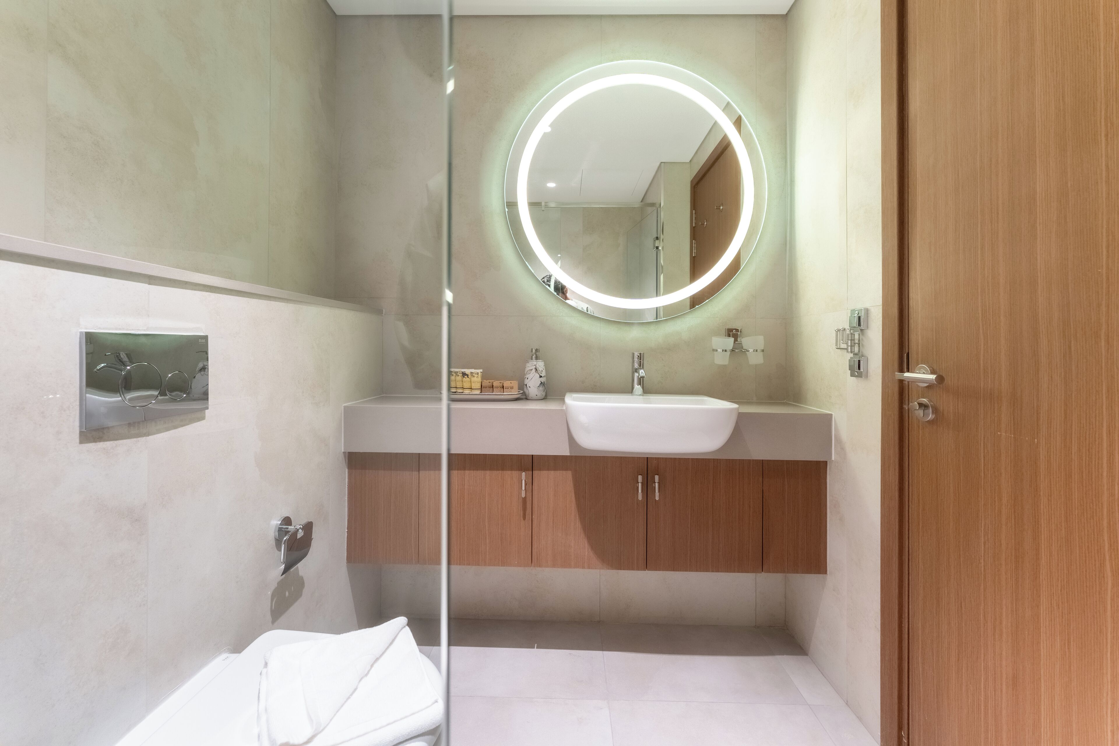 A modern bathroom with a glass shower enclosure, a white sink, and a wooden vanity.