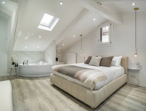 A bedroom with a large bed, a built-in bathtub, and a skylight. - Calle Varisco Apartment with Terrace R&R (Venecia)