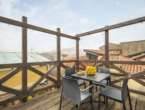 A wooden deck with a table and chairs, overlooking a cityscape with terracotta roofs. - Calle Varisco Apartment with Terrace R&R (Venecia)