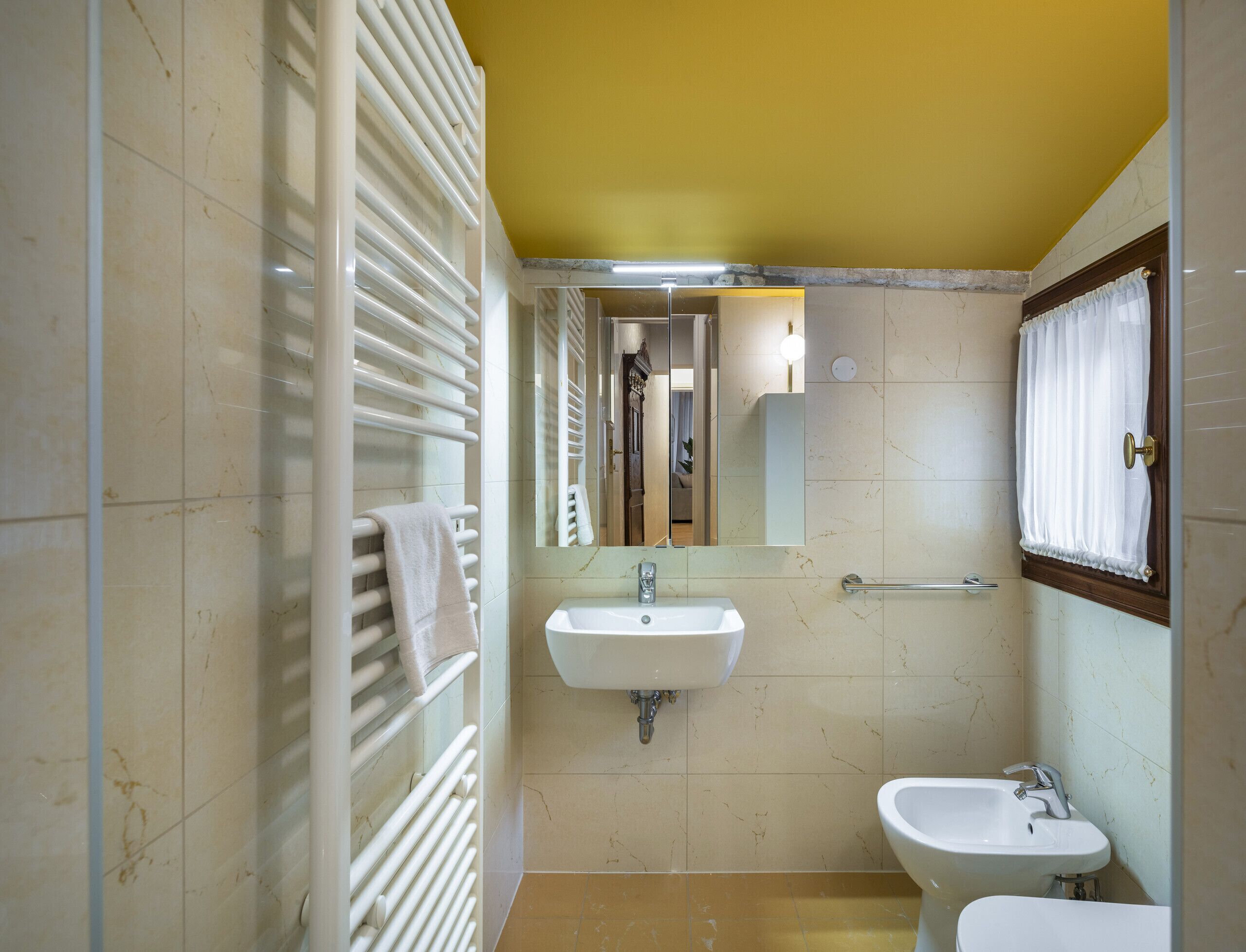 A bathroom with a white sink, a mirror, a towel rack, and a shower area.