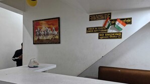 A room with a white table, a framed picture of horses, and multiple signs including one for check-in/out times and a no smoking sign. - Shri Krishna Niwas (Mathura)