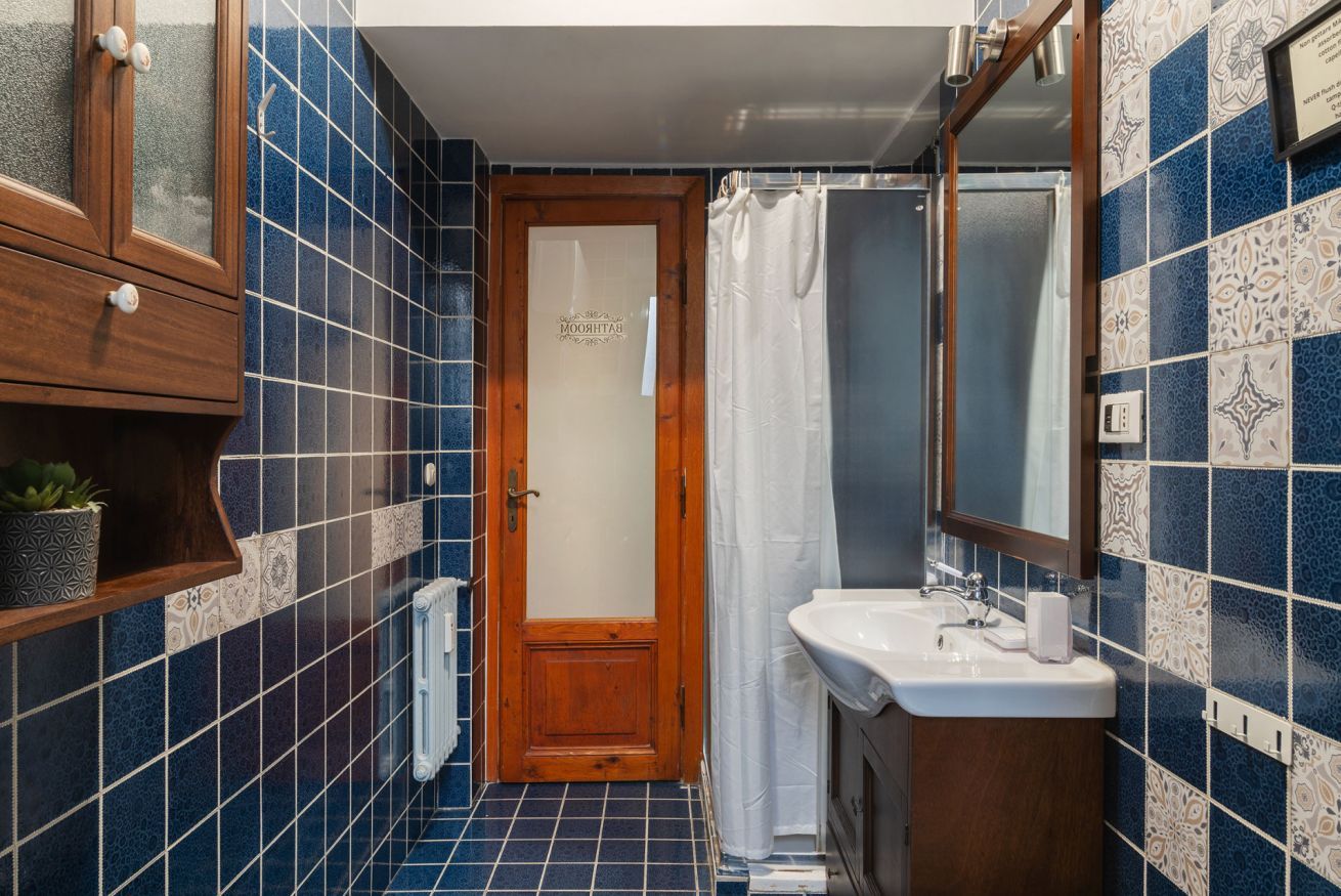 A bathroom with a wooden door, a white sink, and a mirror.