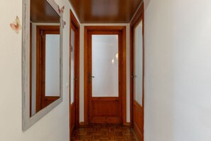 A hallway with wooden doors and a mirrored wall. - GuestHost - Cozy 90m2 apartment, perfect for 4 people, located on the ground floor of a typical building with cloister.The accommodation is located in the Re di Roma/San Giovanni district, a lively and central residential and commercial area.The city's (Rome)