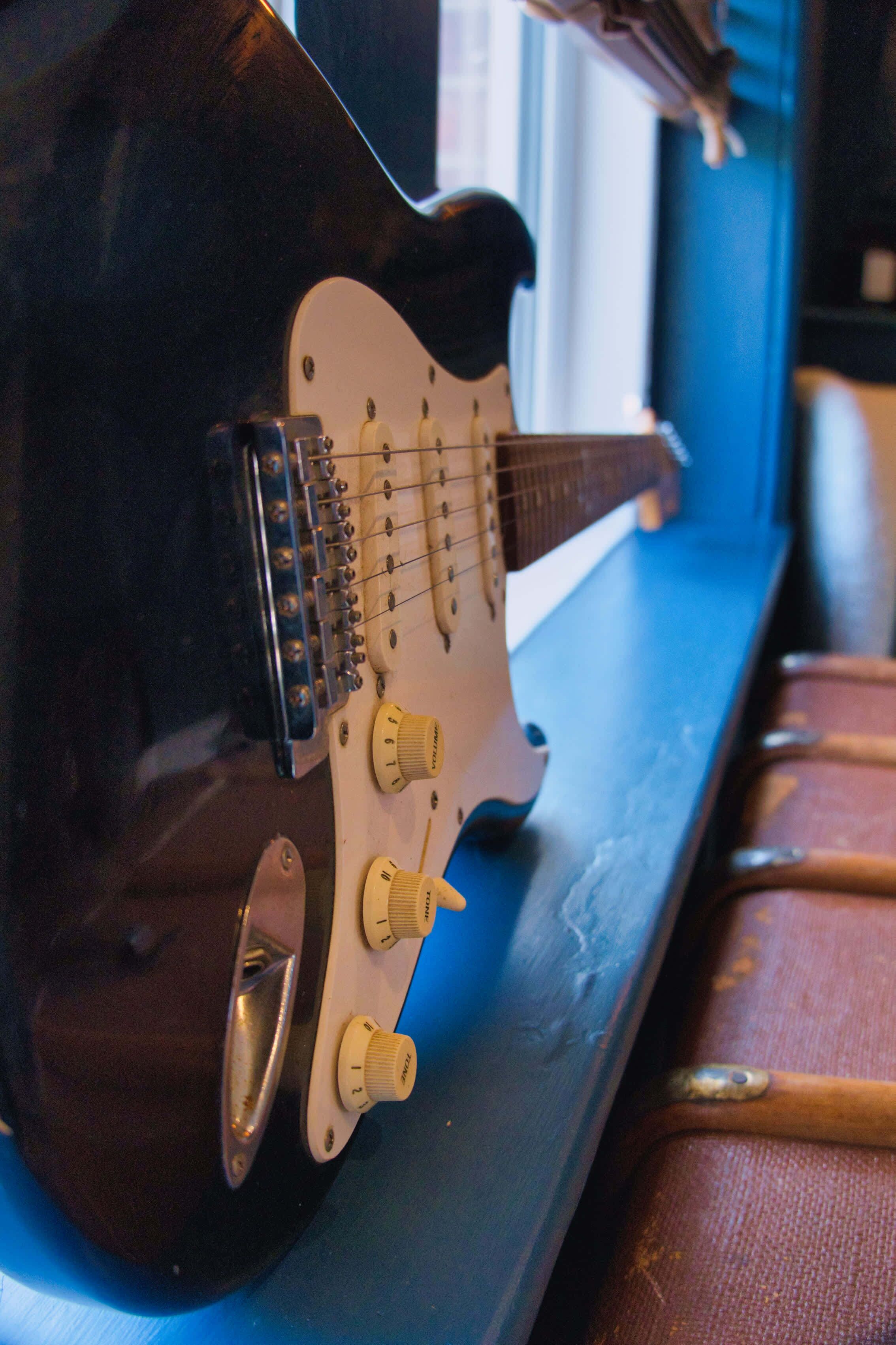 A guitar on a blue surface with a window in the background.