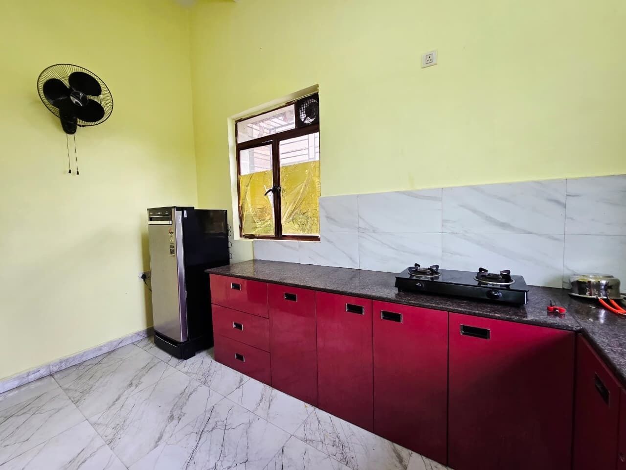 A kitchen with a refrigerator, a gas stove, and cabinets.