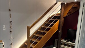 A staircase with wooden steps and a handrail, leading to a landing with a television and storage cabinets. - Detached chalet 100m2 open view (Xonrupt-Longemer)