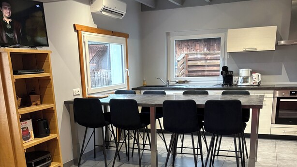 A modern kitchen with a dining area, a TV, and a bookshelf. - Detached chalet 100m2 open view (Xonrupt-Longemer)