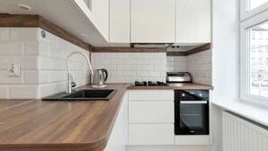 Una cucina moderna con pensili bianchi, un piano di lavoro in legno, un forno integrato e una finestra che lascia entrare luce naturale.