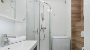 Un bagno moderno con cabina doccia in vetro, lavandino bianco e servizi igienici.