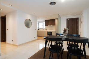 Una cocina moderna con electrodomésticos integrados, un comedor con mesa y sillas, y un espejo grande en la pared.