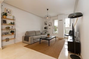 A modern living room with a sofa, coffee table, and a bookshelf. - Acqua by Time & Home (San Pedro de Alcántara)