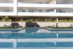 A swimming pool with lounge chairs and a lifeguard stand. - Acqua by Time & Home (San Pedro de Alcántara)