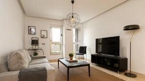 A living room with a sofa, coffee table, TV, and a floor lamp. - Acqua by Time & Home (San Pedro de Alcántara)