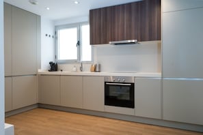Una cocina moderna con horno empotrado, ventana y armario superior de madera.