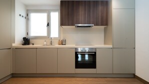 A modern kitchen with light-colored cabinets, a built-in oven, and a window above the sink. - Acqua by Time & Home (San Pedro de Alcántara)