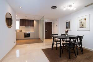 Eine moderne Küche mit Essbereich, ausgestattet mit einem großen Tisch, Stühlen, Holzboden und einem großen Spiegel an der Wand.