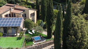 Een huis met zonnepanelen, een zwembad en een verzorgde tuin.