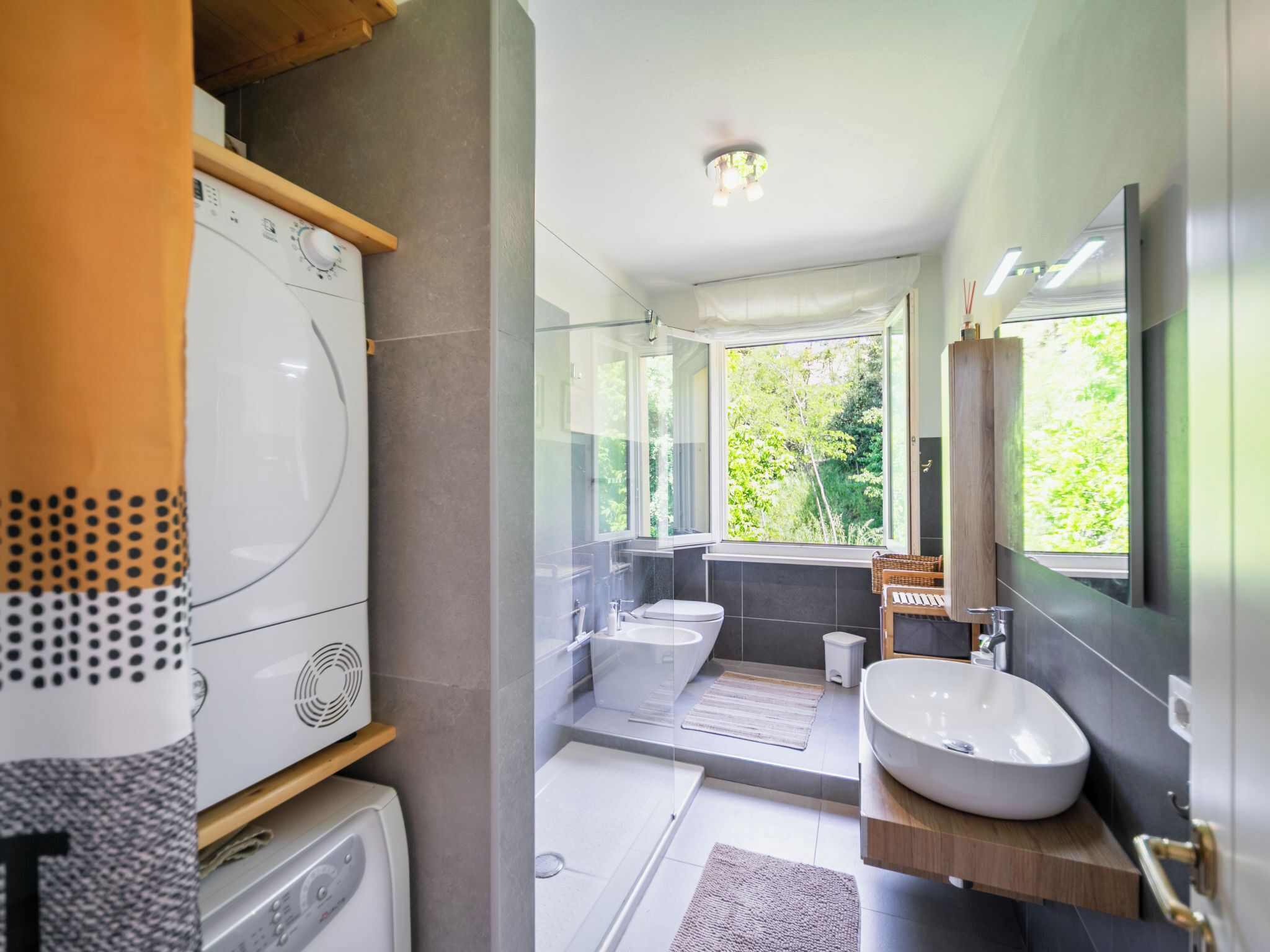 A modern bathroom with a large mirror, a freestanding bathtub, a sink, and a toilet.