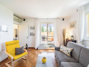 Ein modernes Wohnzimmer mit einem gelben Sessel, einem grauen Sofa und einer Glastür, die in einen Außenbereich führt.