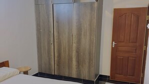 Ein Schlafzimmer mit einem Bett, einem Holzschrank, einem kleinen runden Tisch und einer Tür.