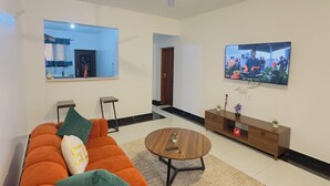Ein modernes Wohnzimmer mit einem Ecksofa, einem Couchtisch, einem Fernseher und einem Deckenventilator.