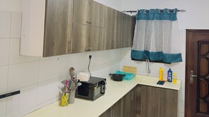 Eine moderne Küche mit Holzschränken, einem Gasherd, einer Mikrowelle und einem Spülbecken mit blauer Fußmatte.