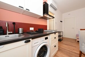 A compact kitchen with a washing machine, a sink, and a black countertop. - Garden Apartment Bardolino - Coral Apartment (Bardolino)