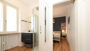 A modern bathroom with a glass shower enclosure, a white sink, and a wooden floor. - Garden Apartment Bardolino - Coral Apartment (Bardolino)