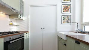 Eine Küche mit Herd, Backofen und Spüle. An der Wand befinden sich Bilder in Rahmen.