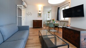 Ein modernes Wohnzimmer mit einer Couch, einem Glastisch, einem Holzschrank und einem flachbildfernseher, der an der Wand befestigt ist.