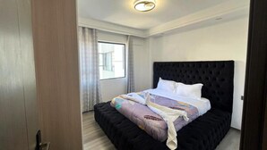 A bedroom with a large bed, a dark headboard, and a window with curtains. - Nairobi Accomodation (Nairobi)